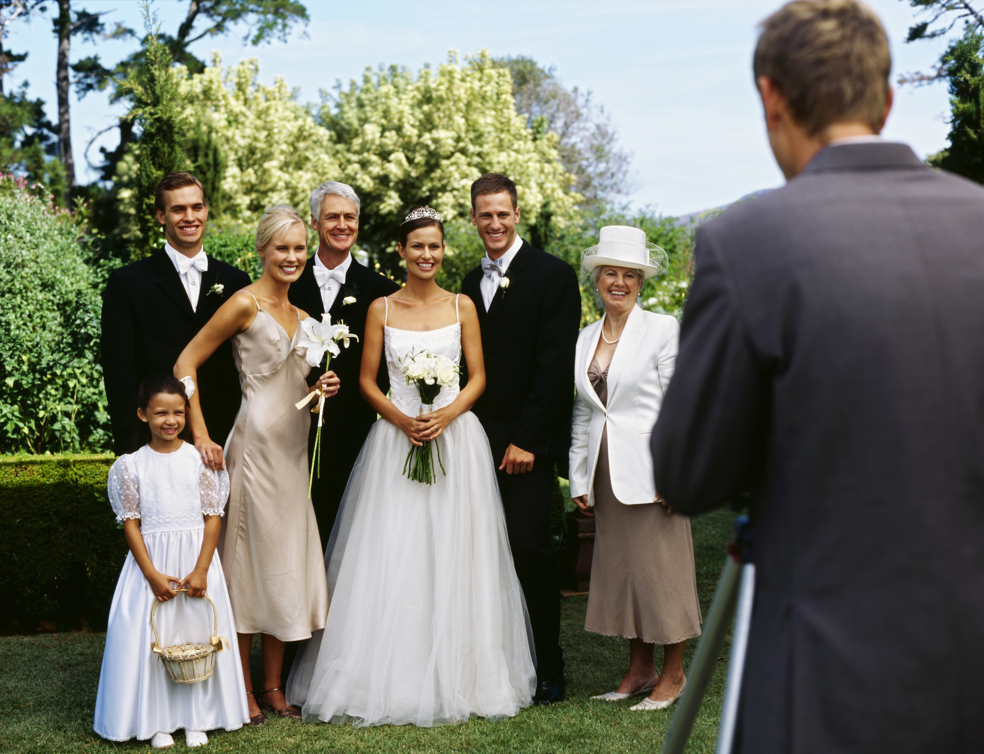 Wedding photo of a couple with family and photographer in foreground