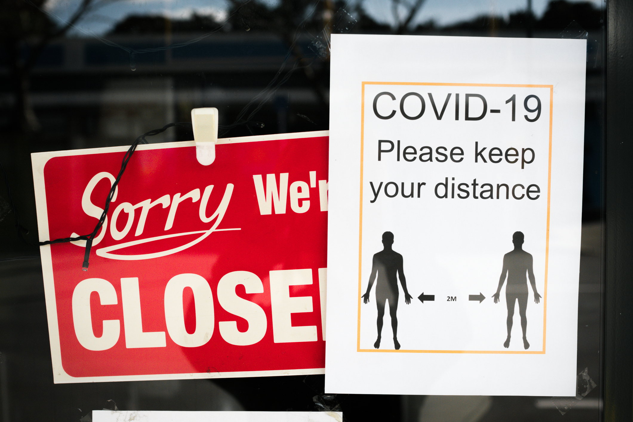 Signs on a door indicating closure and advising to maintain a 2-meter distance due to COVID-19
