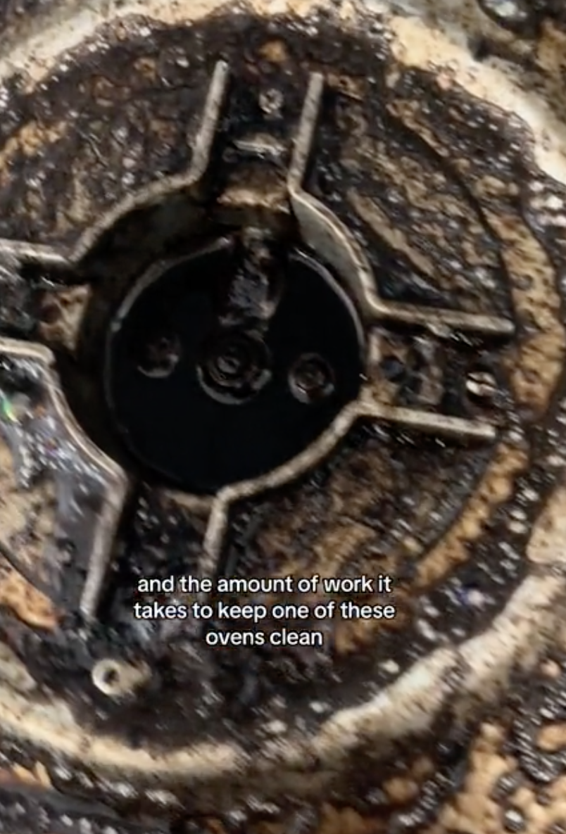 Close-up of a dirty gas stove burner with text about the effort required to clean it