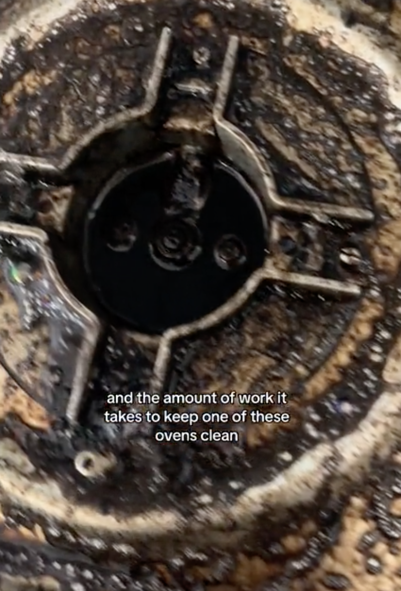 Close-up of a dirty gas stove burner with text about the effort required to clean it