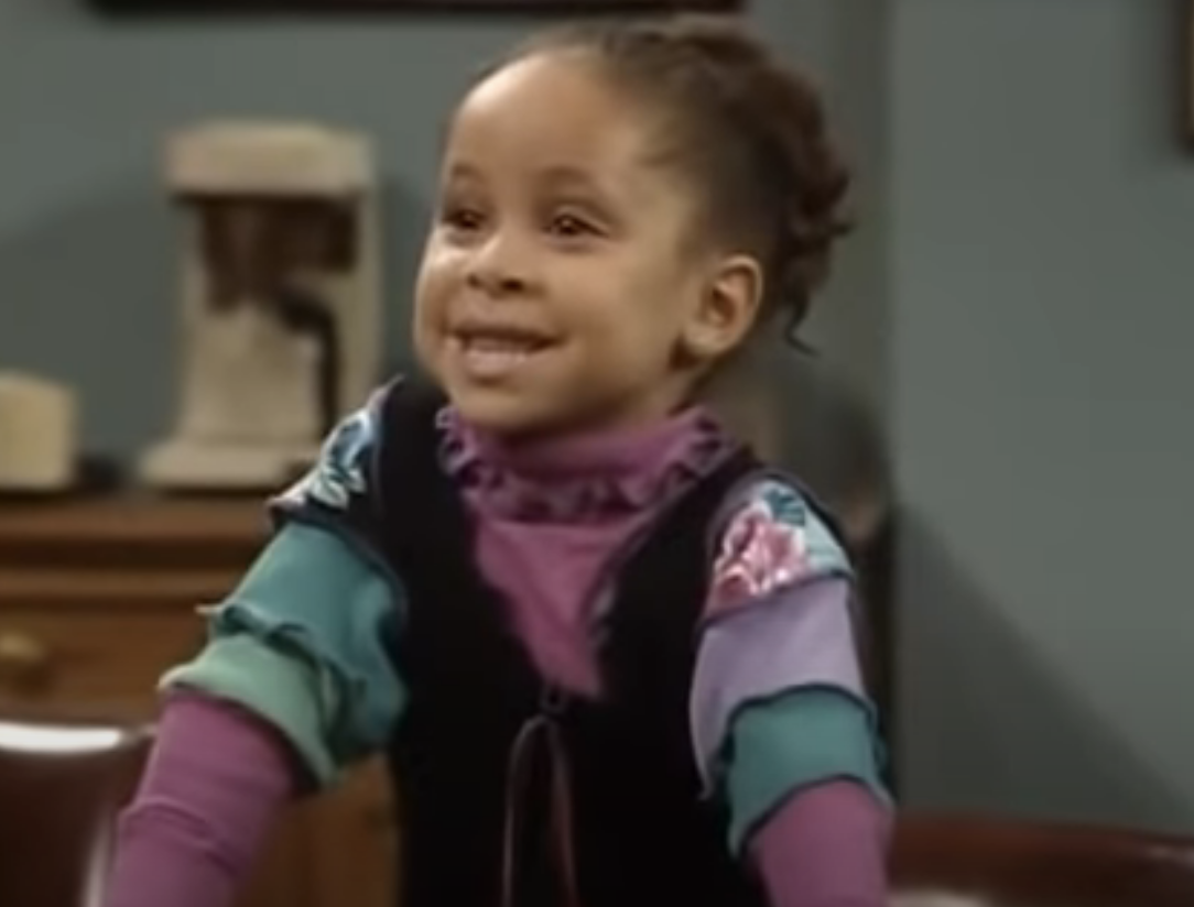 Young Raven in character wearing a layered outfit, smiling