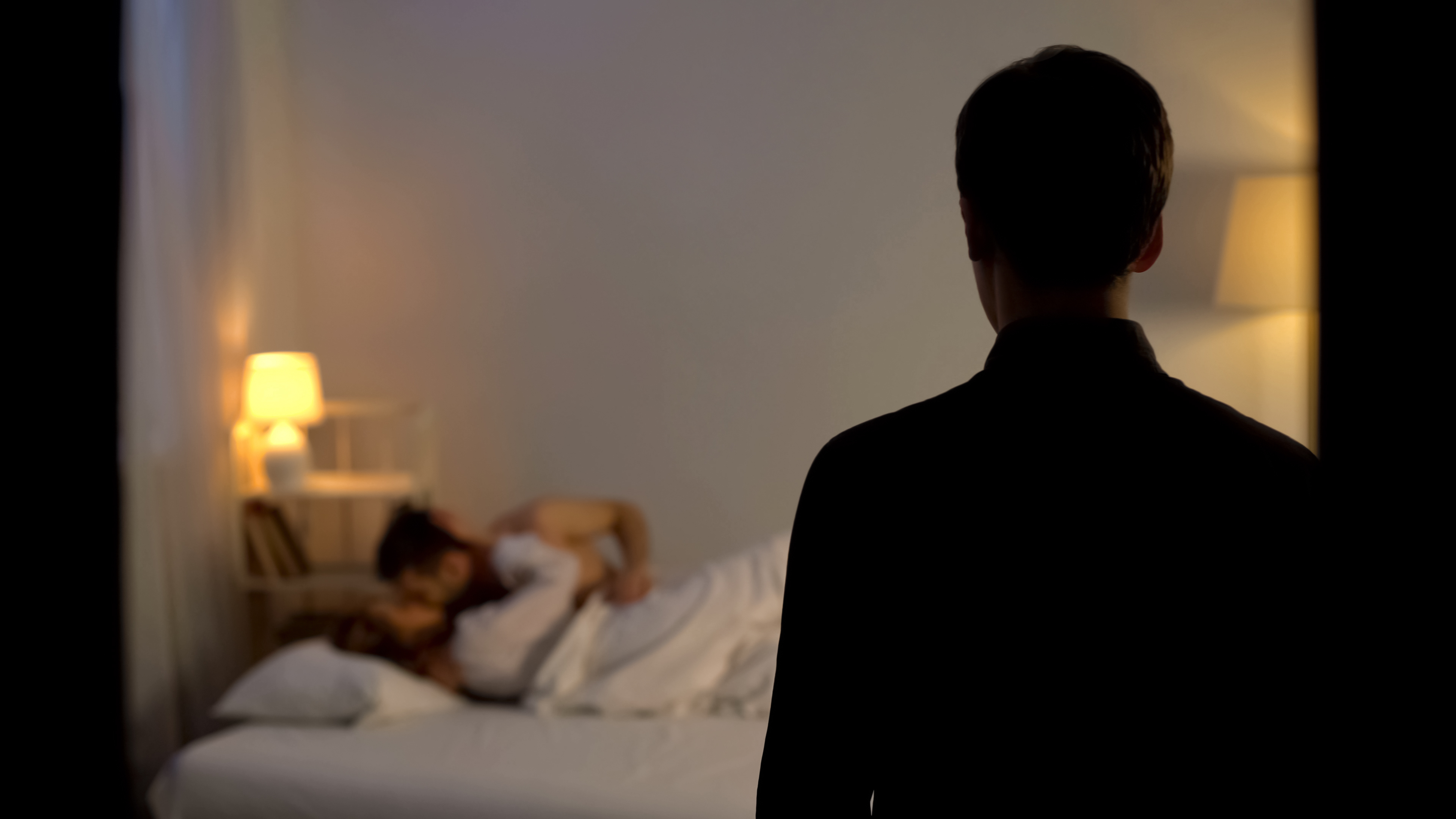 Woman walking in to find husband in bed with someone else