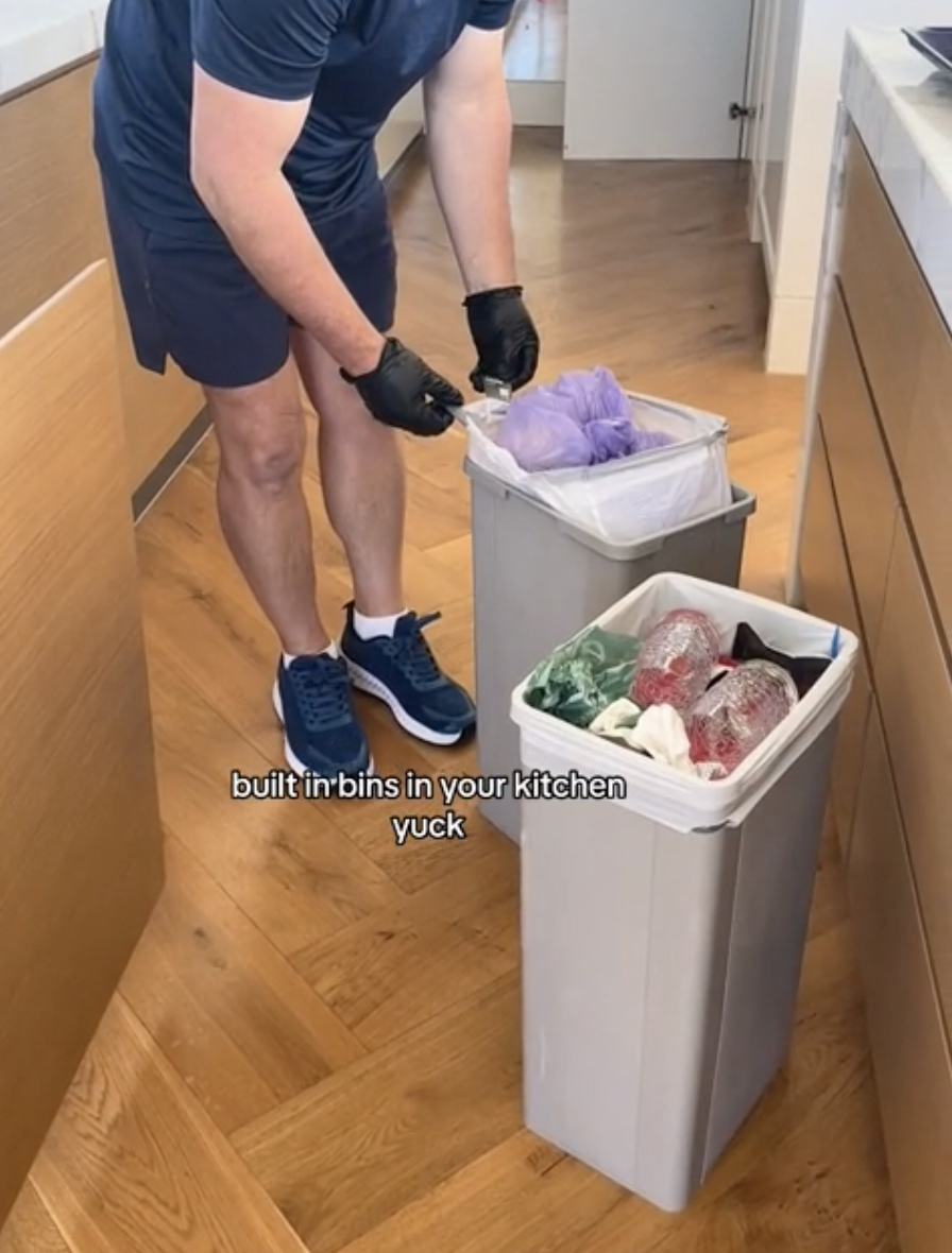 Man tying up trash bags in their  kitchen bins