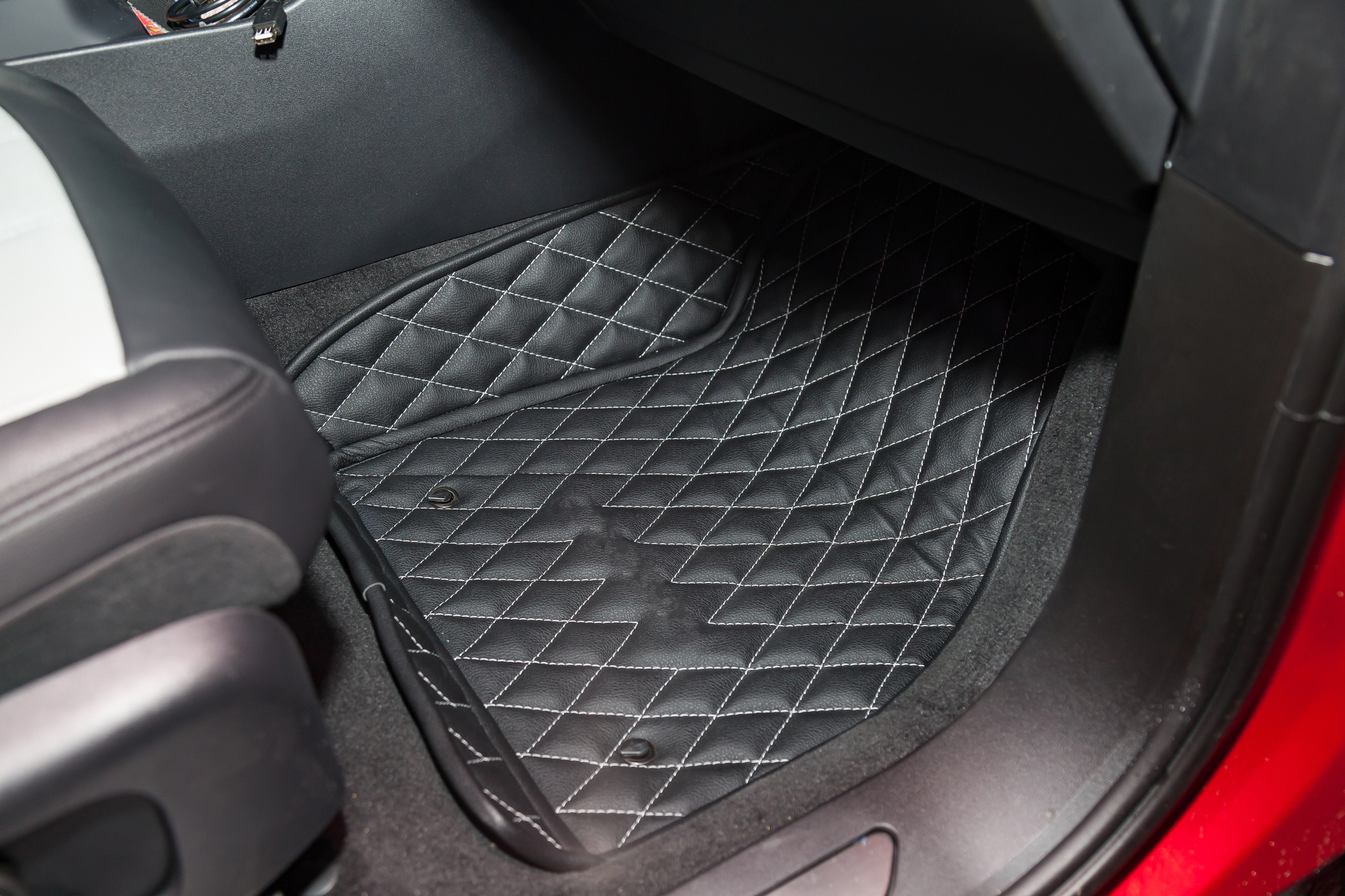 A close-up of a car&#x27;s footwell with quilted floor mats