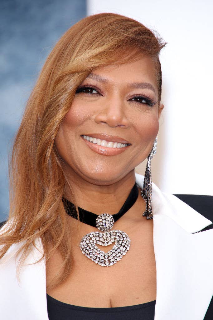 Queen Latifah wearing a tuxedo-inspired outfit with statement jewelry at an event