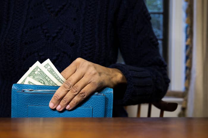 Woman holding a wallet with two $1 bills in it