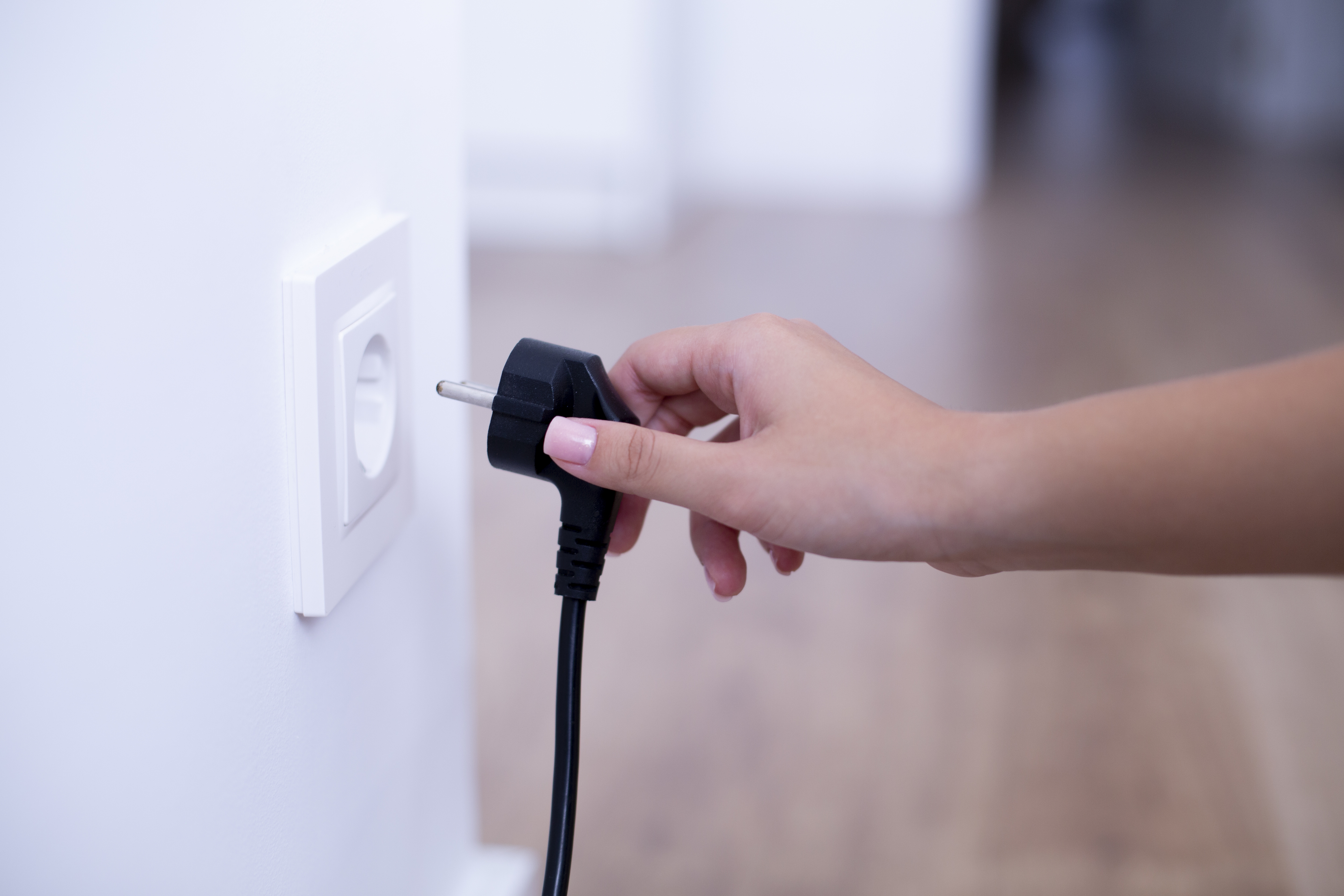 Woman unplugging an appliance from a wall outlet
