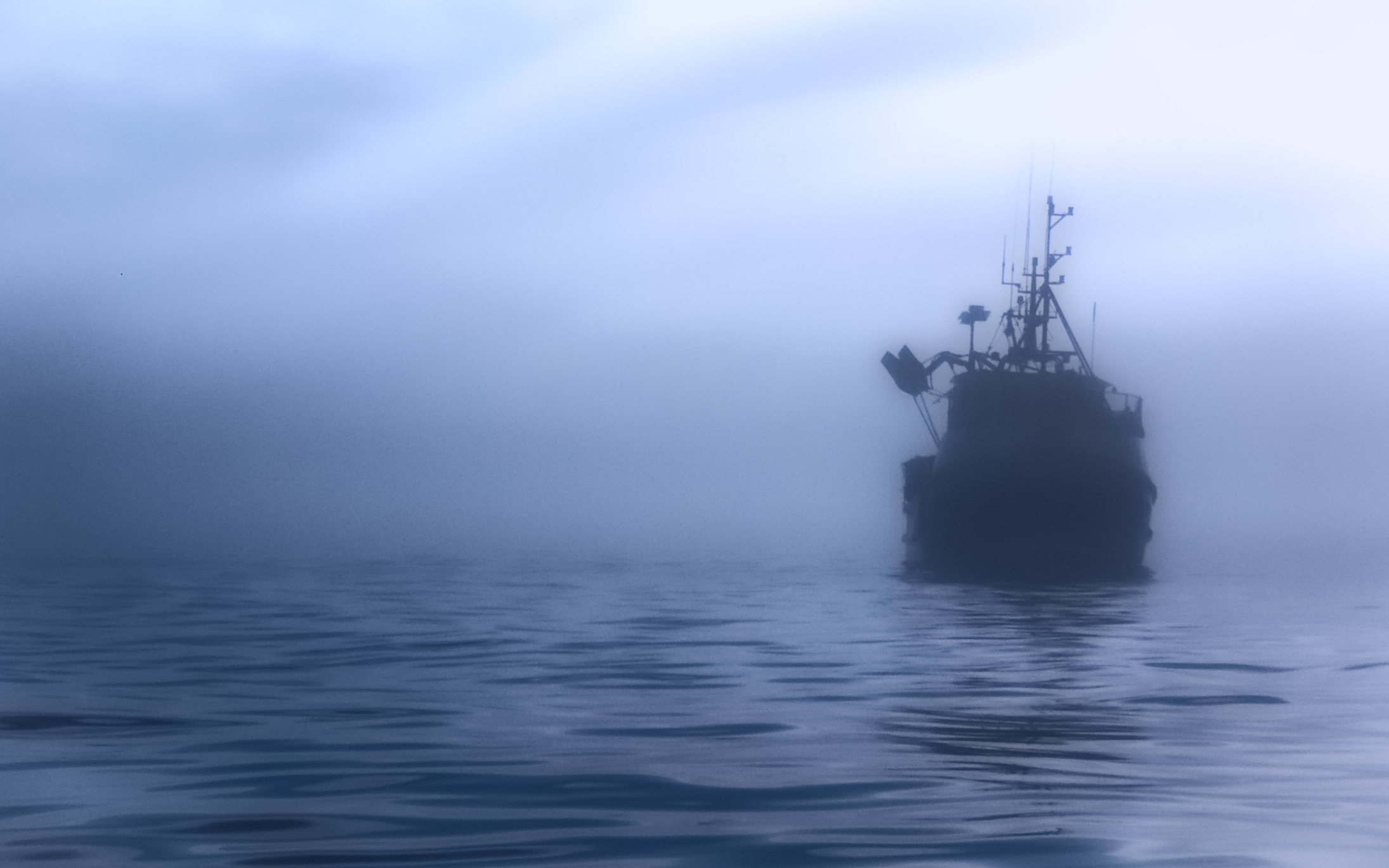 Boat silhouette in mist on calm water