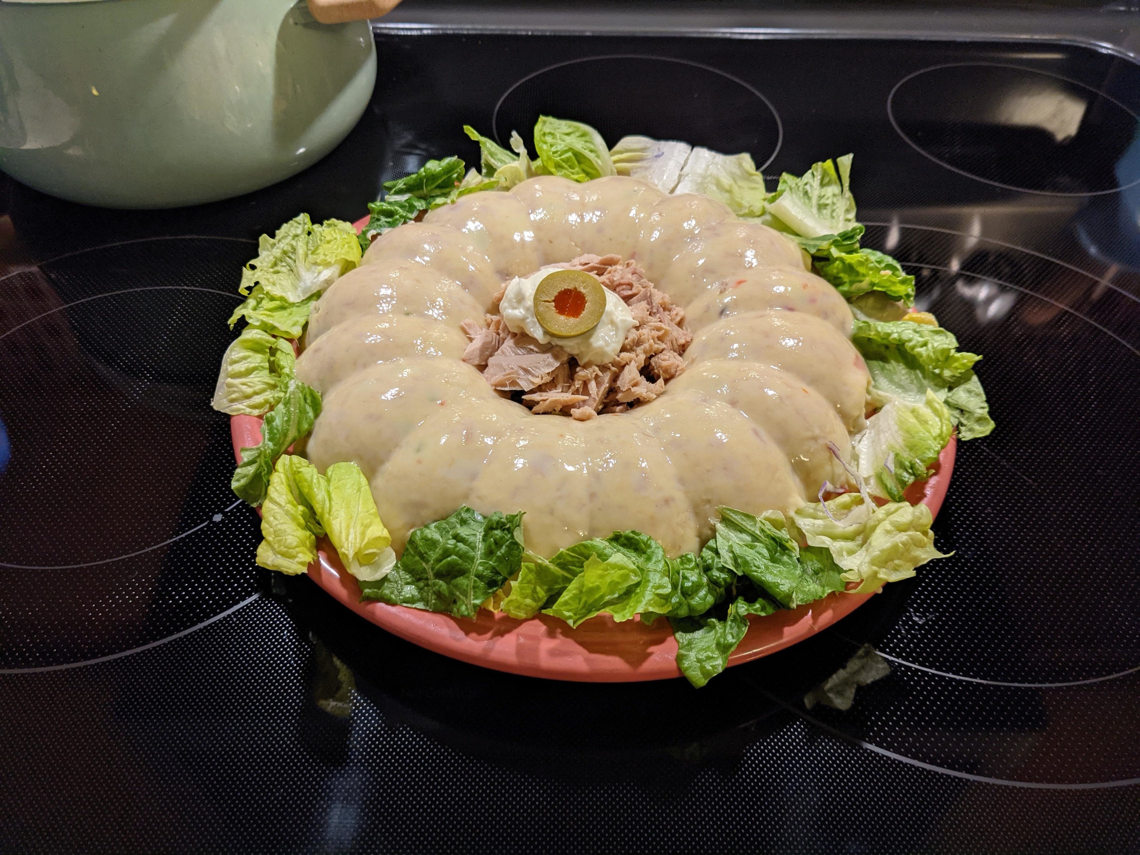 A gelatin salad with creamy dressing and tuna on a bed of lettuce