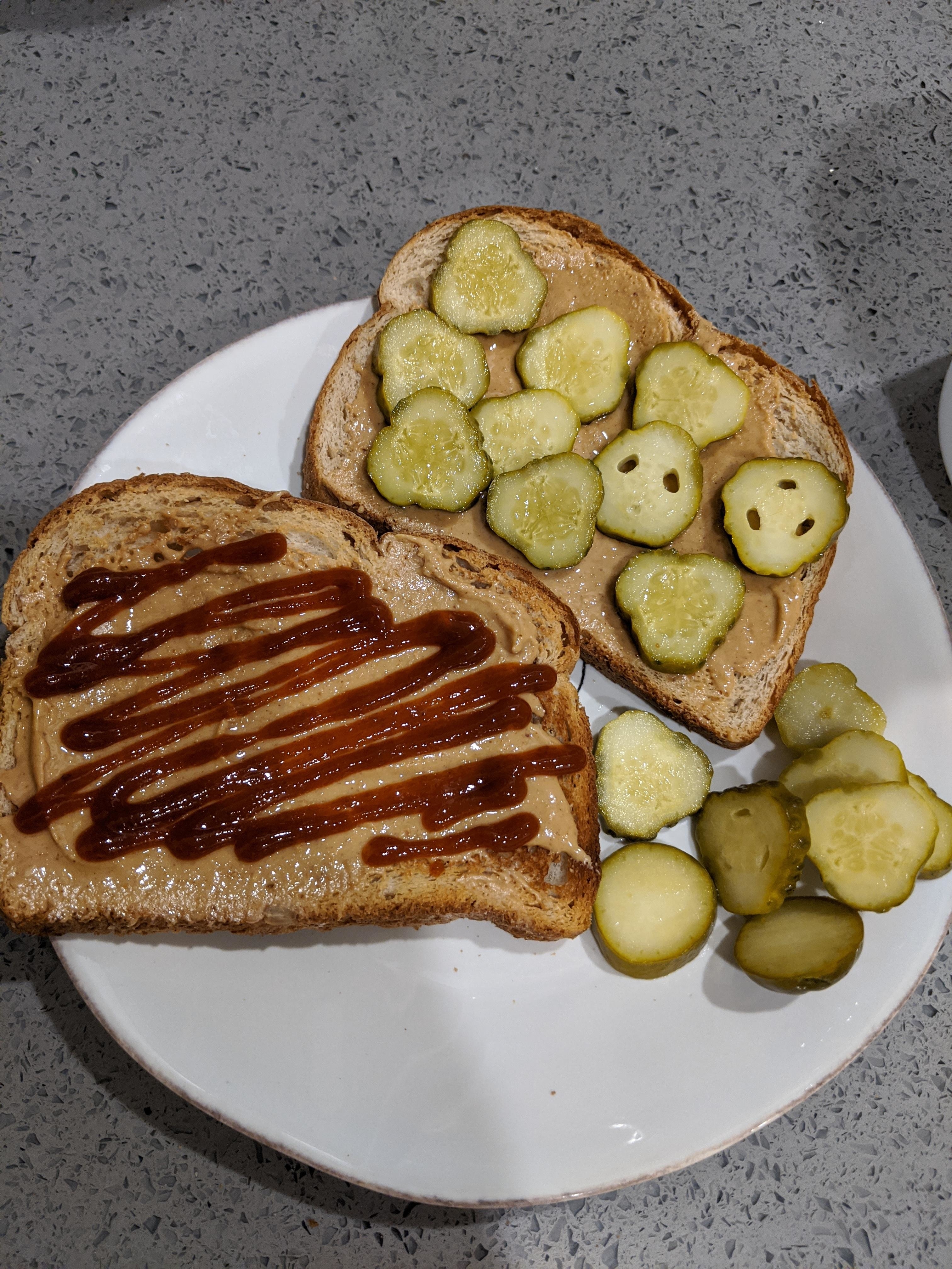 Two slices of bread on a plate; one with peanut butter and pickles, the other with peanut butter and drizzled sriracha