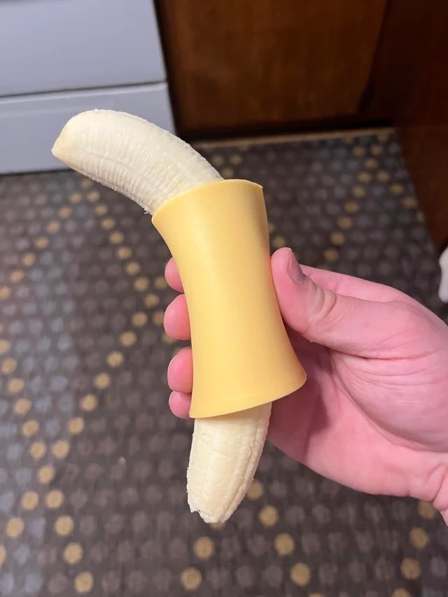 Person holding a banana with a cheese slice wrapped around it