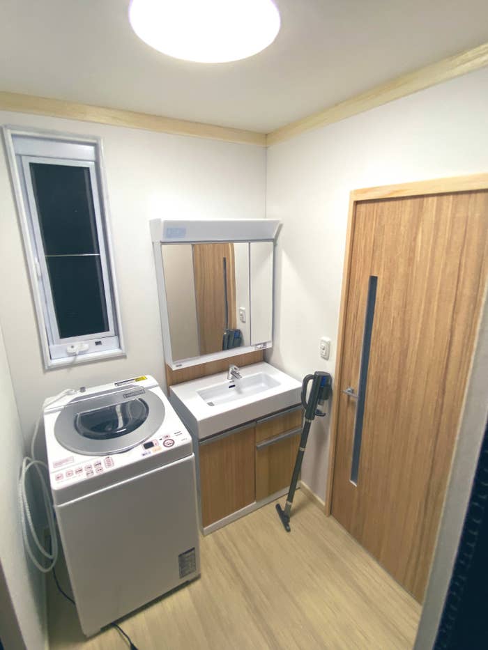 洗濯機とシンクがあるコンパクトなミニチュア洗面室です。