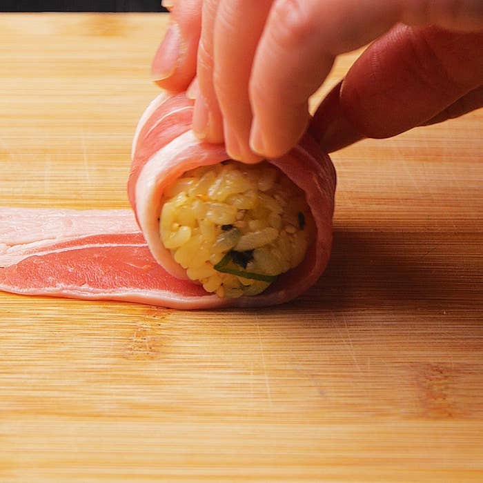 手巻き寿司を作る手順、手が具材をのせたご飯を巻いています。