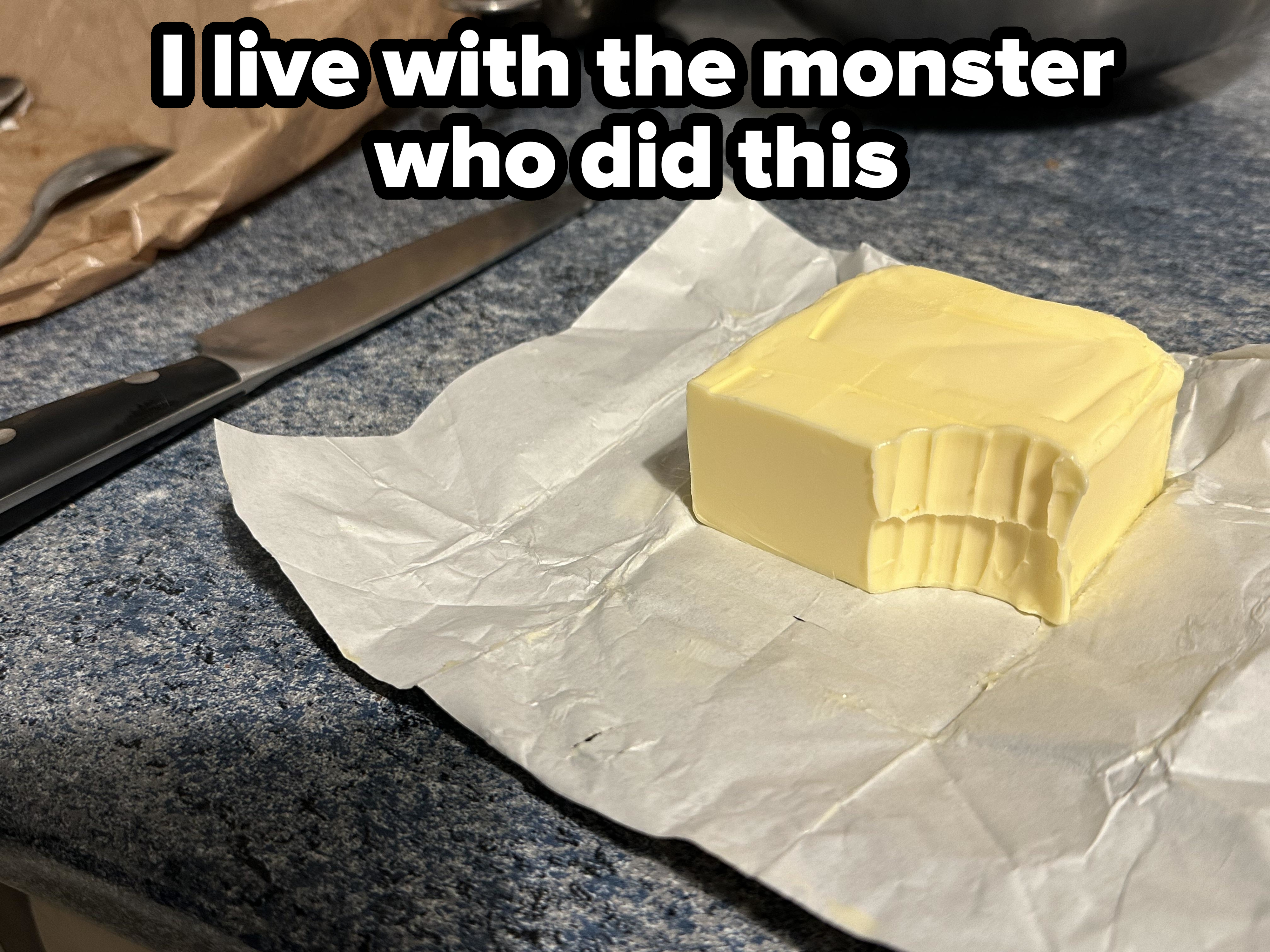 Stick of butter on a kitchen counter with a huge bite taken out of it