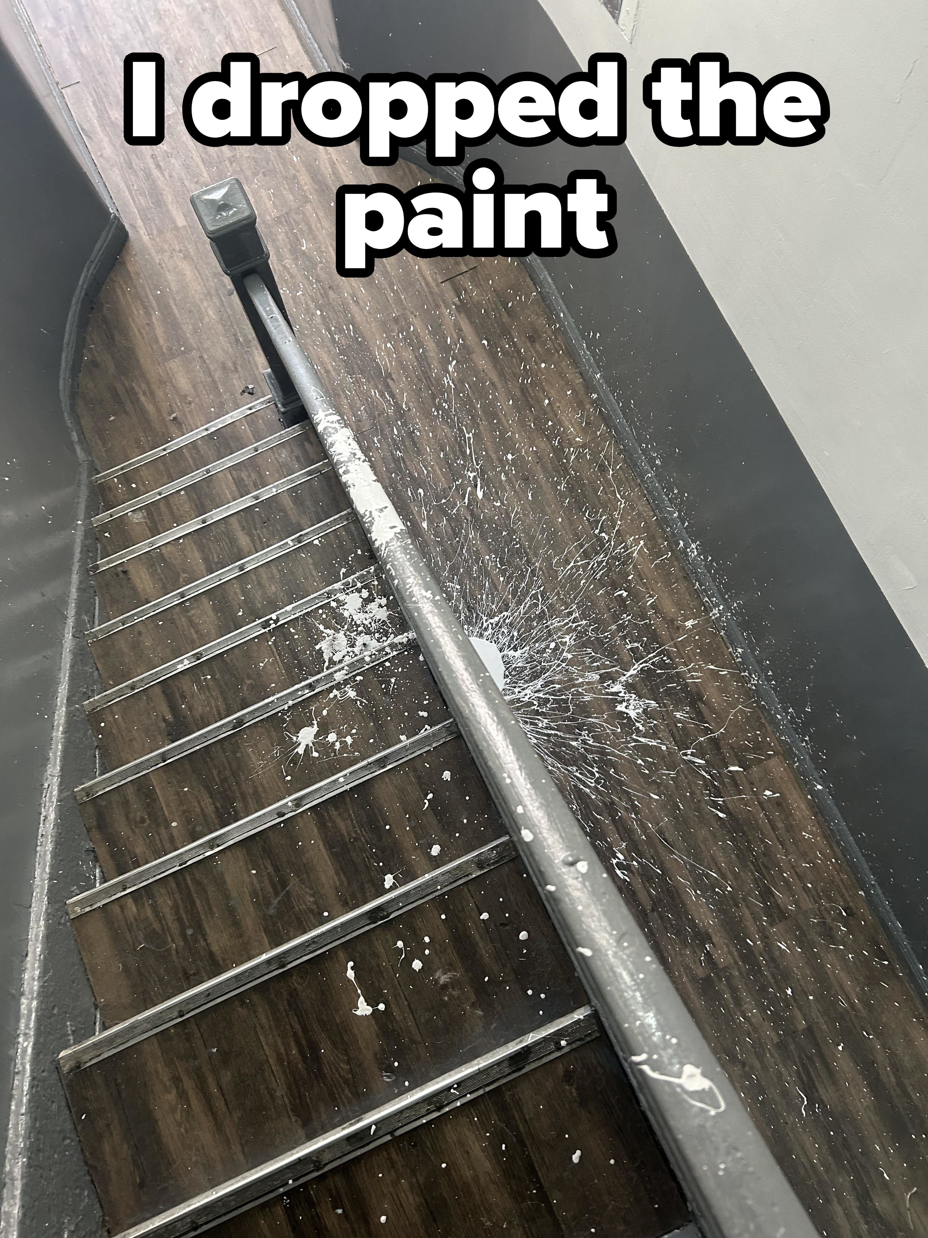 Paint splattered on a wooden staircase next to a metal railing