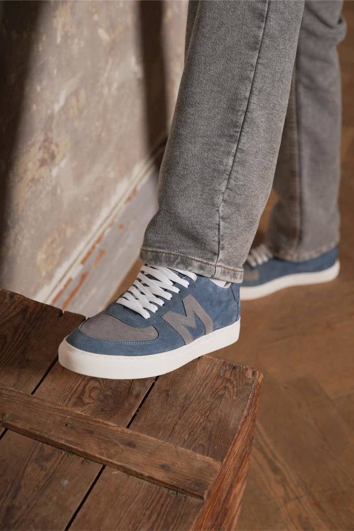 Person wearing grey jeans and blue sneakers stepping on a wooden ledge