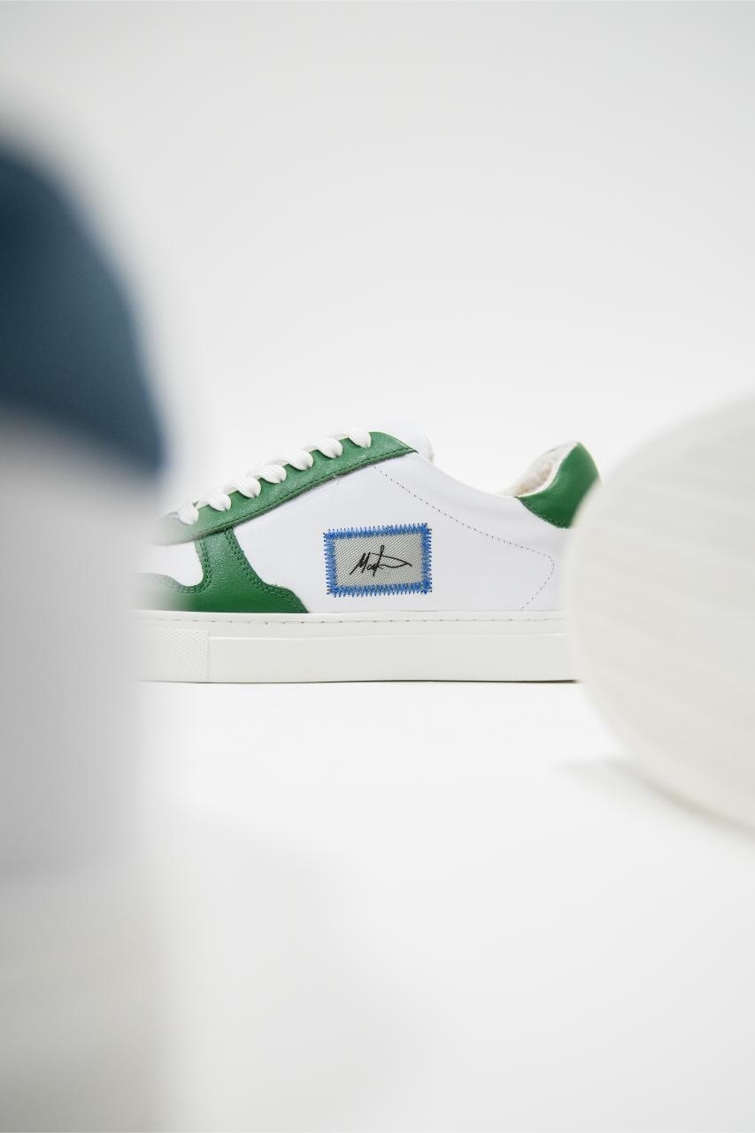 Classic white sneakers with green accents and a blue logo on the side