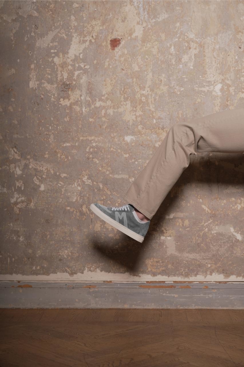 Person&#x27;s lower leg and foot in a sneaker protruding from a wall, giving an illusion of walking through