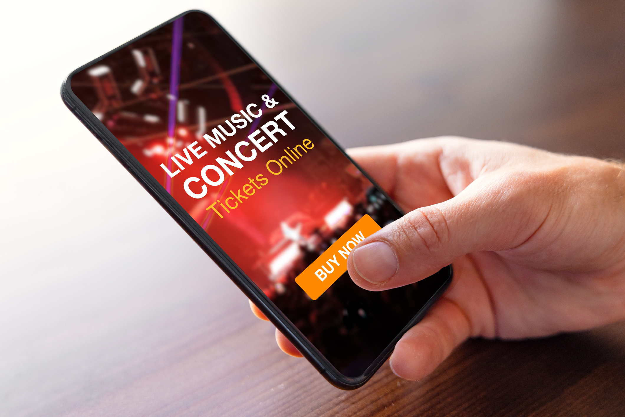 Hand holding a smartphone displaying an ad for live music and concert tickets with a &#x27;Buy Now&#x27; button