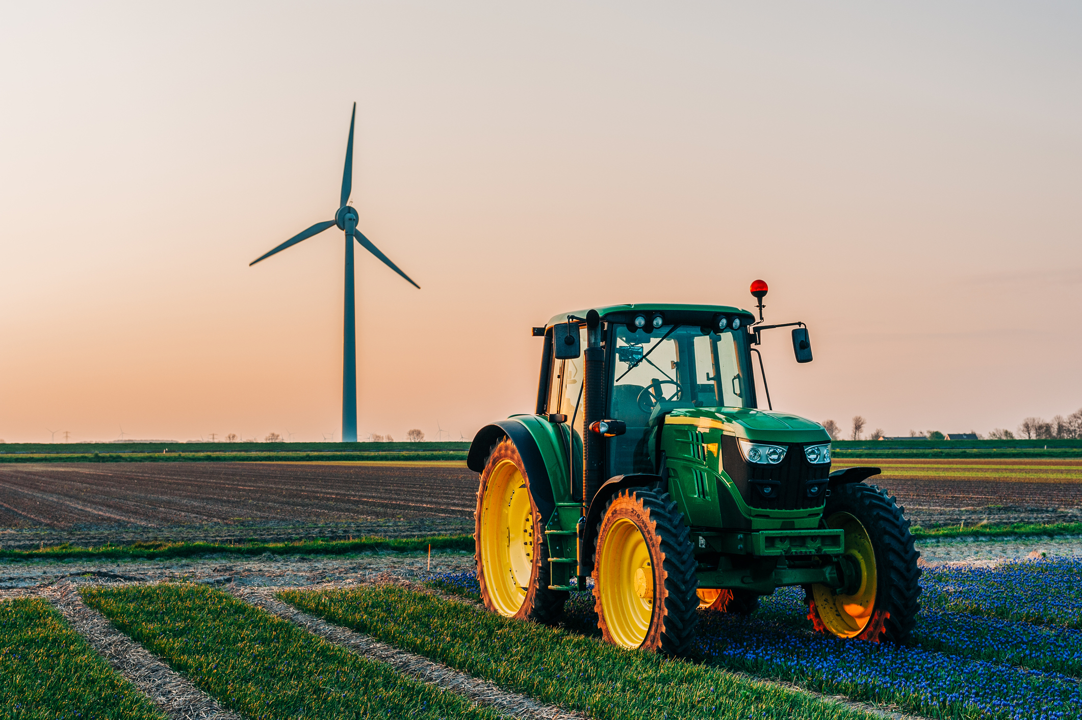 Tractor in a field with a wind turbine in the background