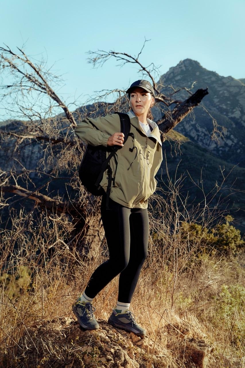 Person in activewear with a backpack posing on a hiking trail