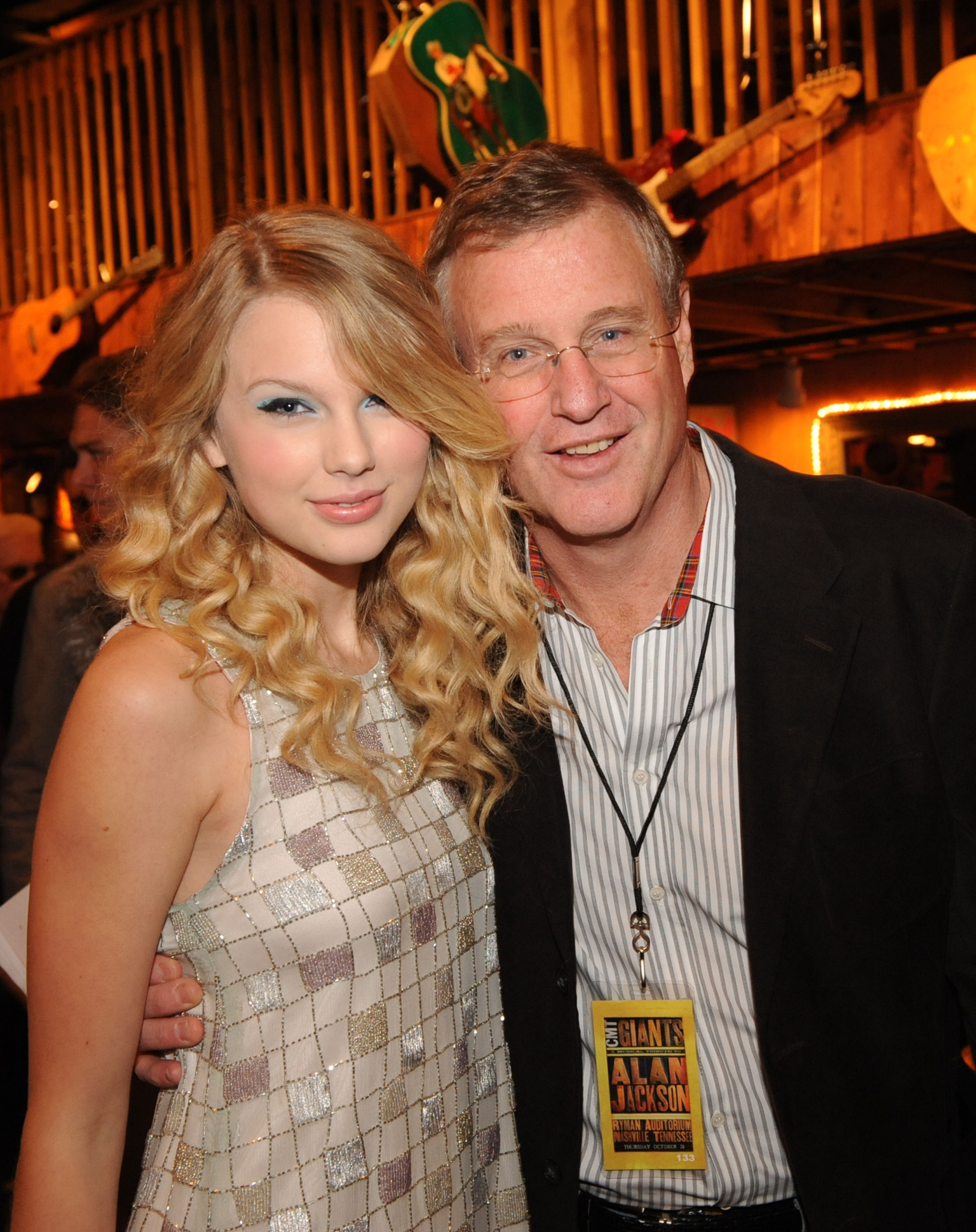 Taylor Swift in a patterned dress with Scott Swift wearing glasses and a lanyard