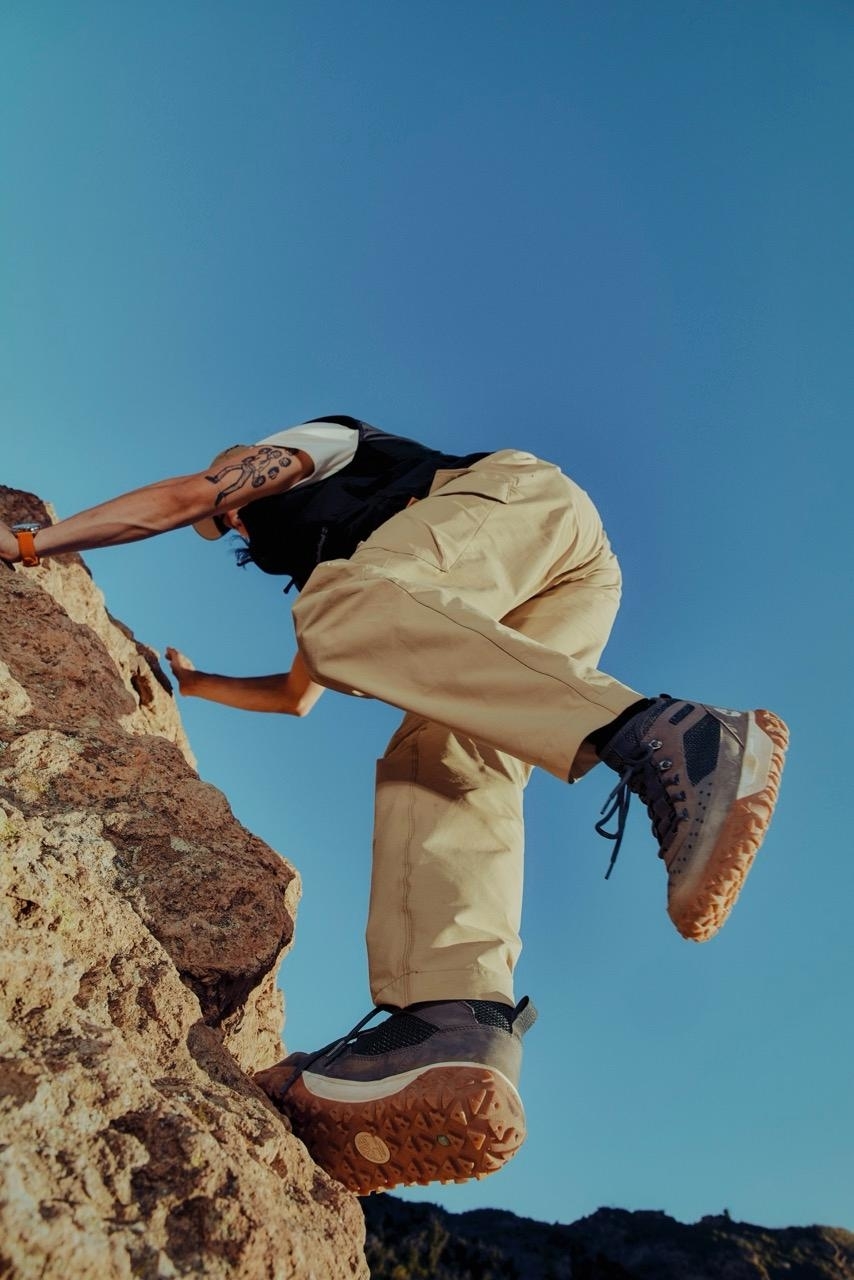 Person in casual wear climbing a rocky terrain, focus on rugged footwear