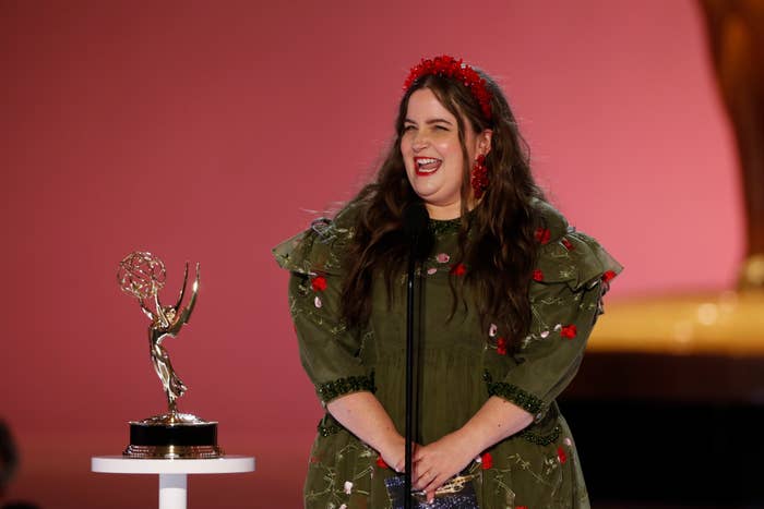 Aidy Bryant onstage next to an Emmy statue