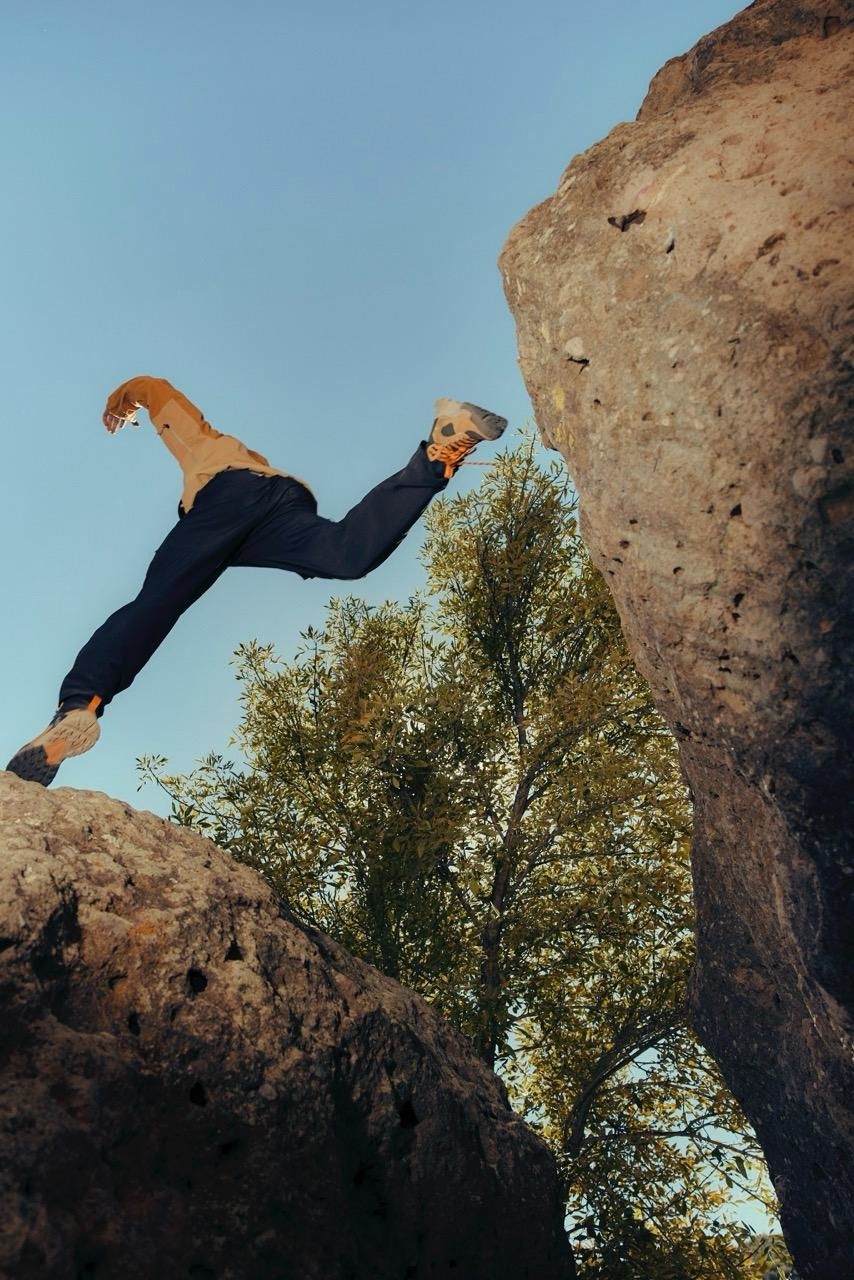 Person in mid-air while rock climbing, with trees in the background