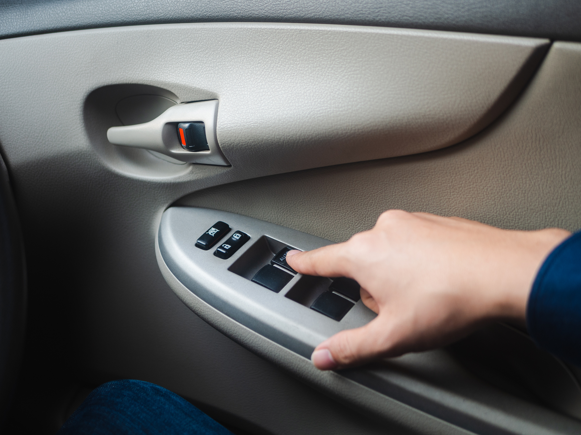 Person&#x27;s hand pressing car door window control buttons
