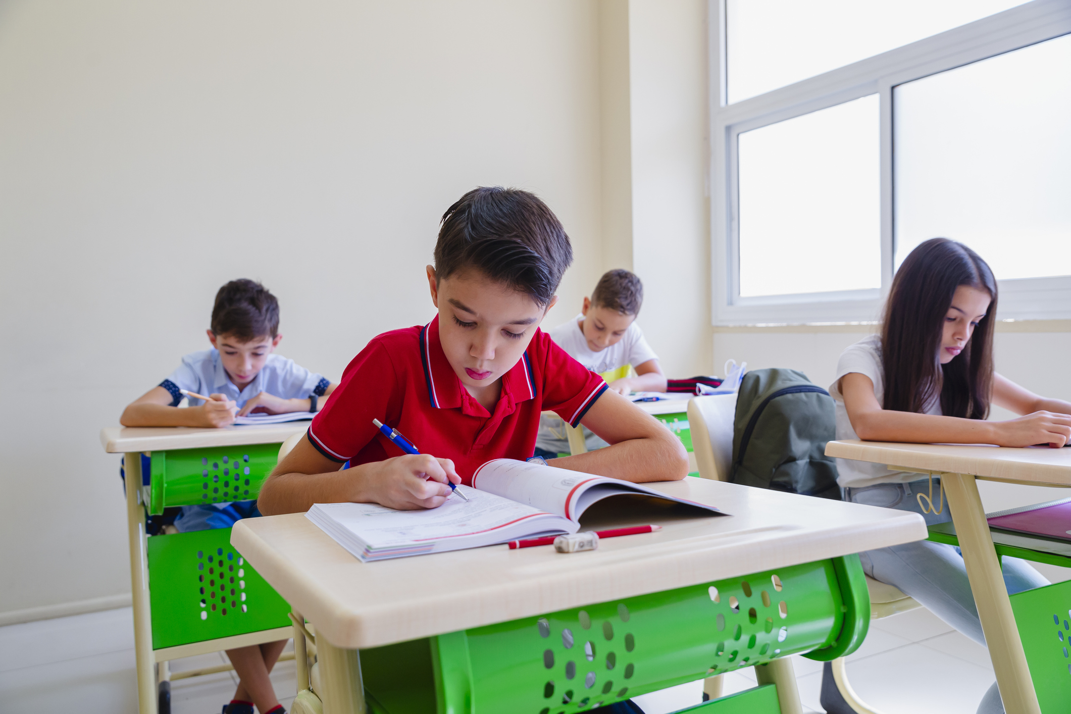 Four students focused on taking a test in a classroom setting