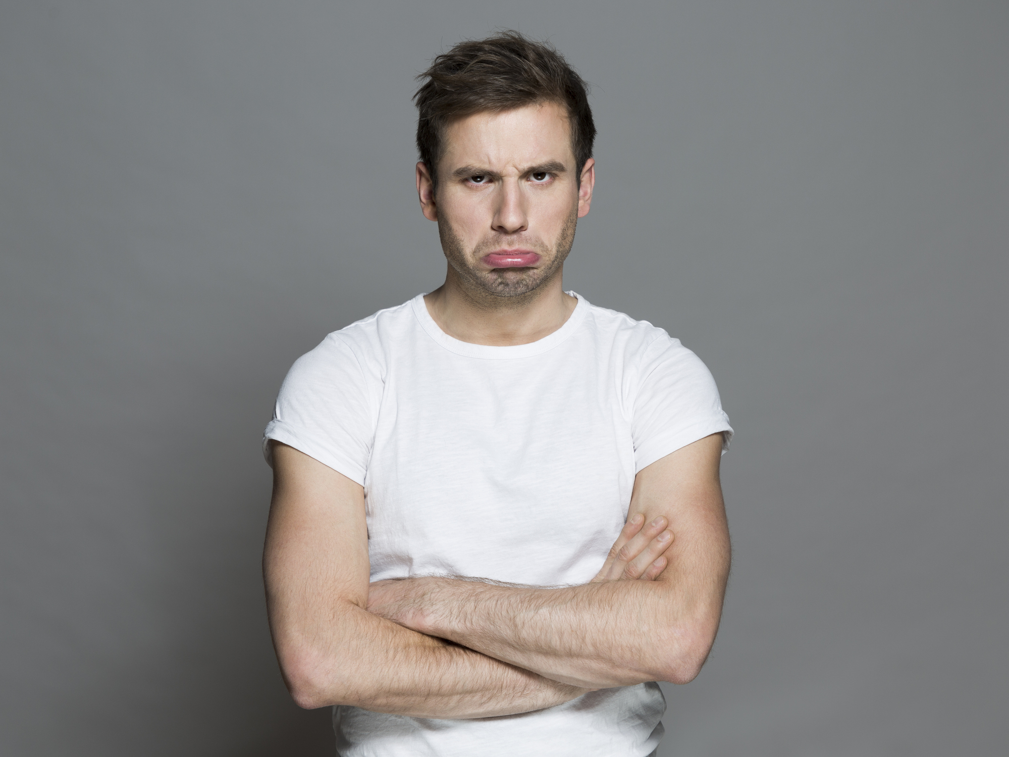 Man with a frown and crossed arms expressing discontent
