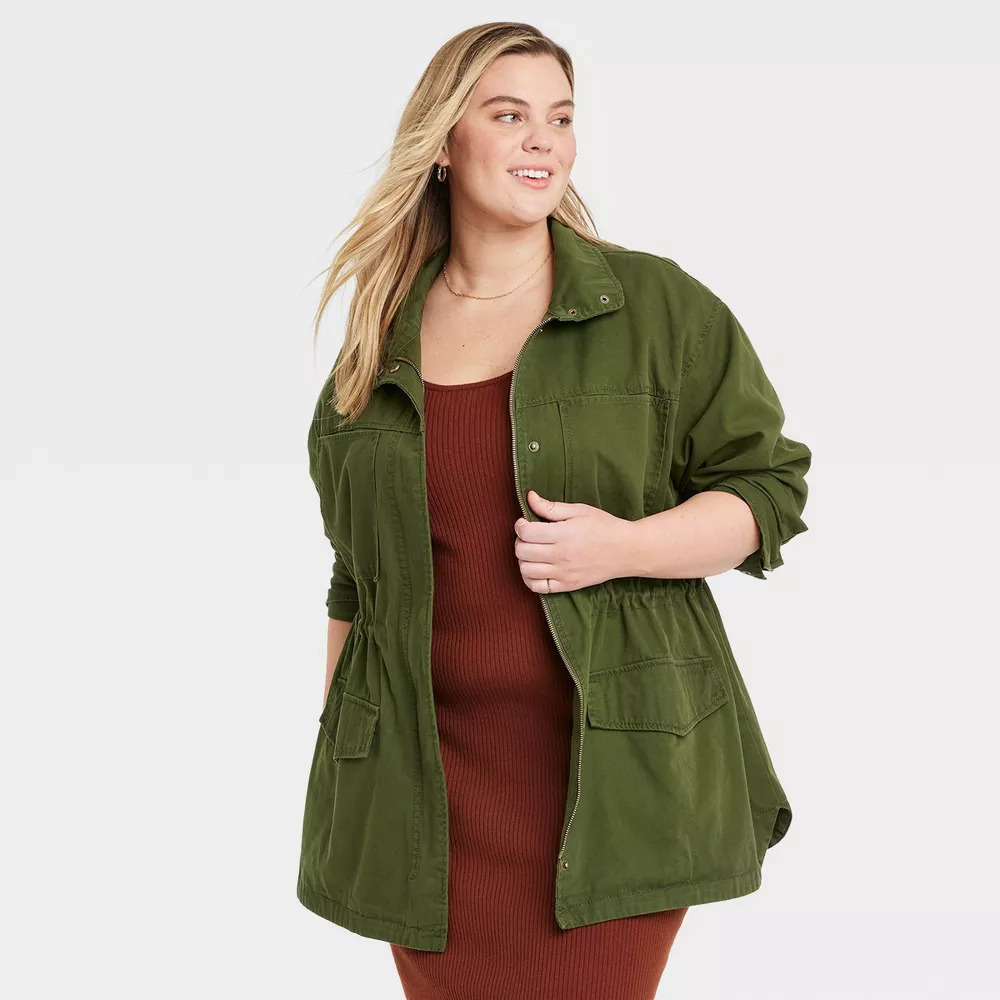 A model wearing the olive green field jacket over a red-brown dress
