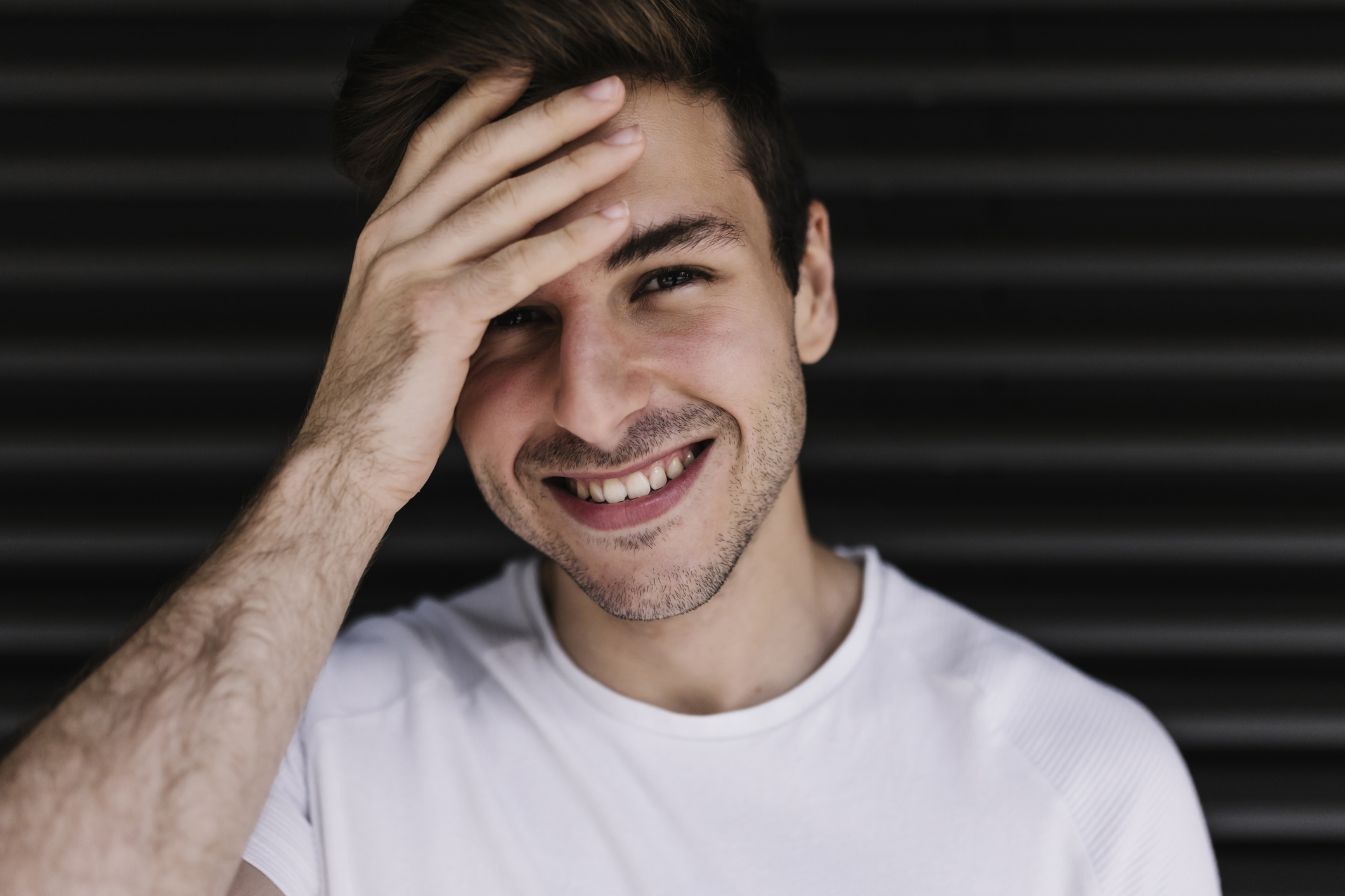 Person smiling with hand partially covering face