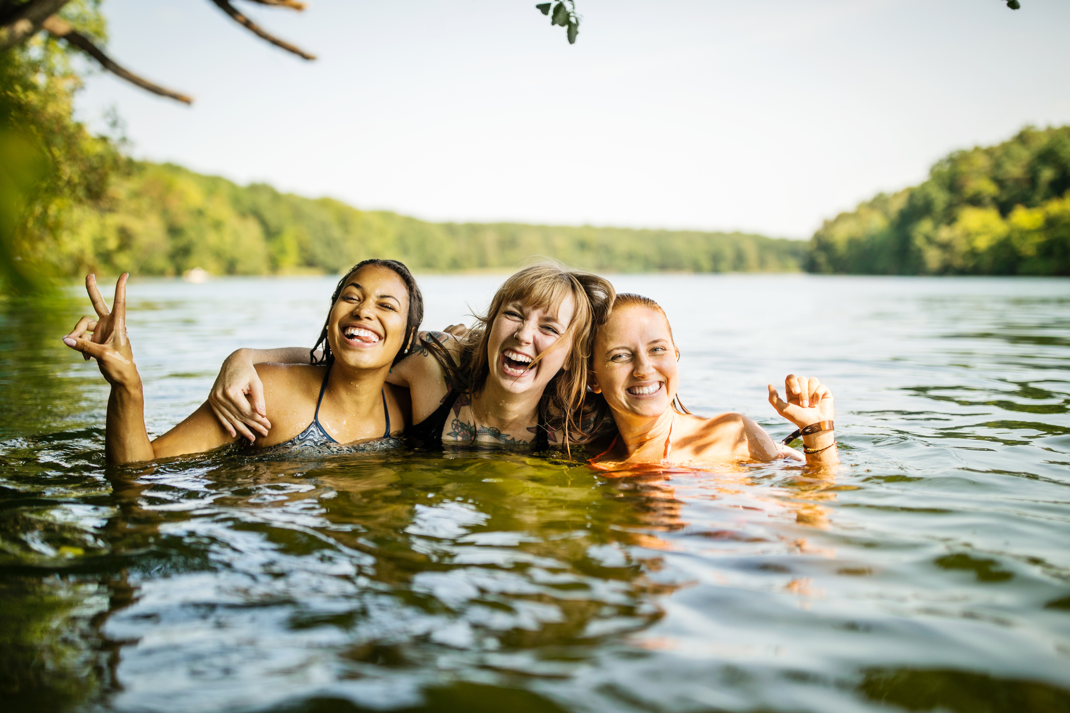 Three friends smiling and posing together in a lake