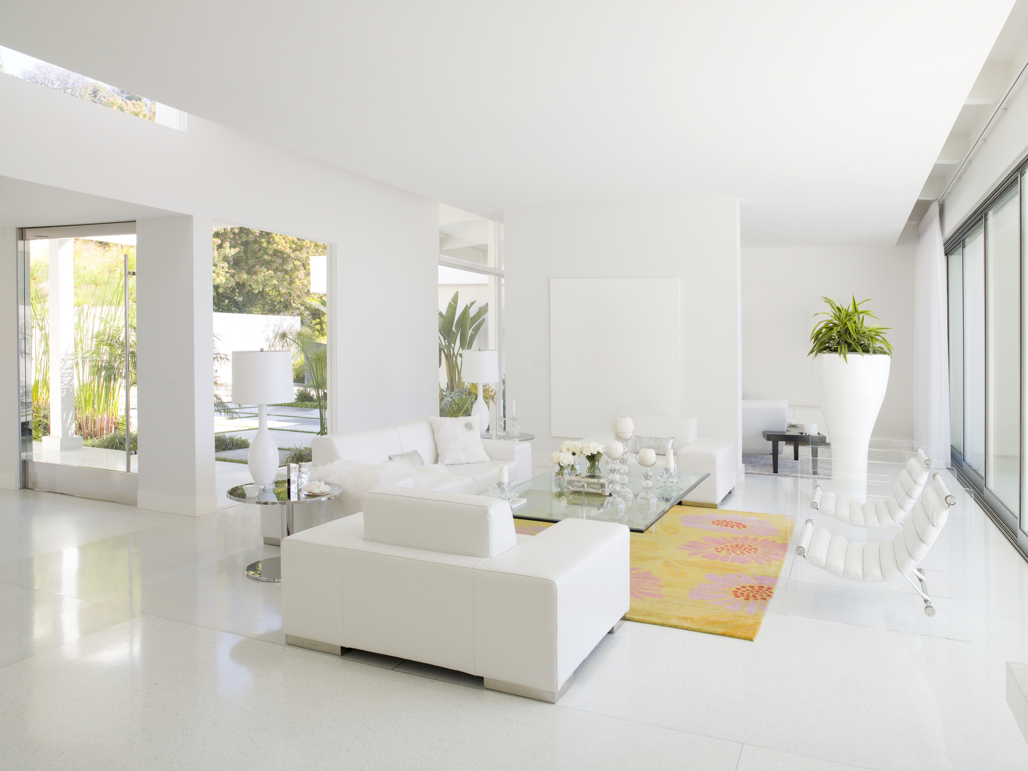 Modern living room with white furniture, minimalist decor, and a bright colored rug