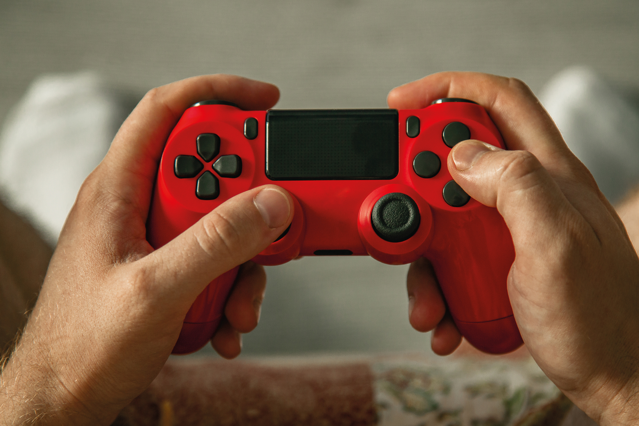 Two hands holding a red game controller, viewed from the player&#x27;s perspective