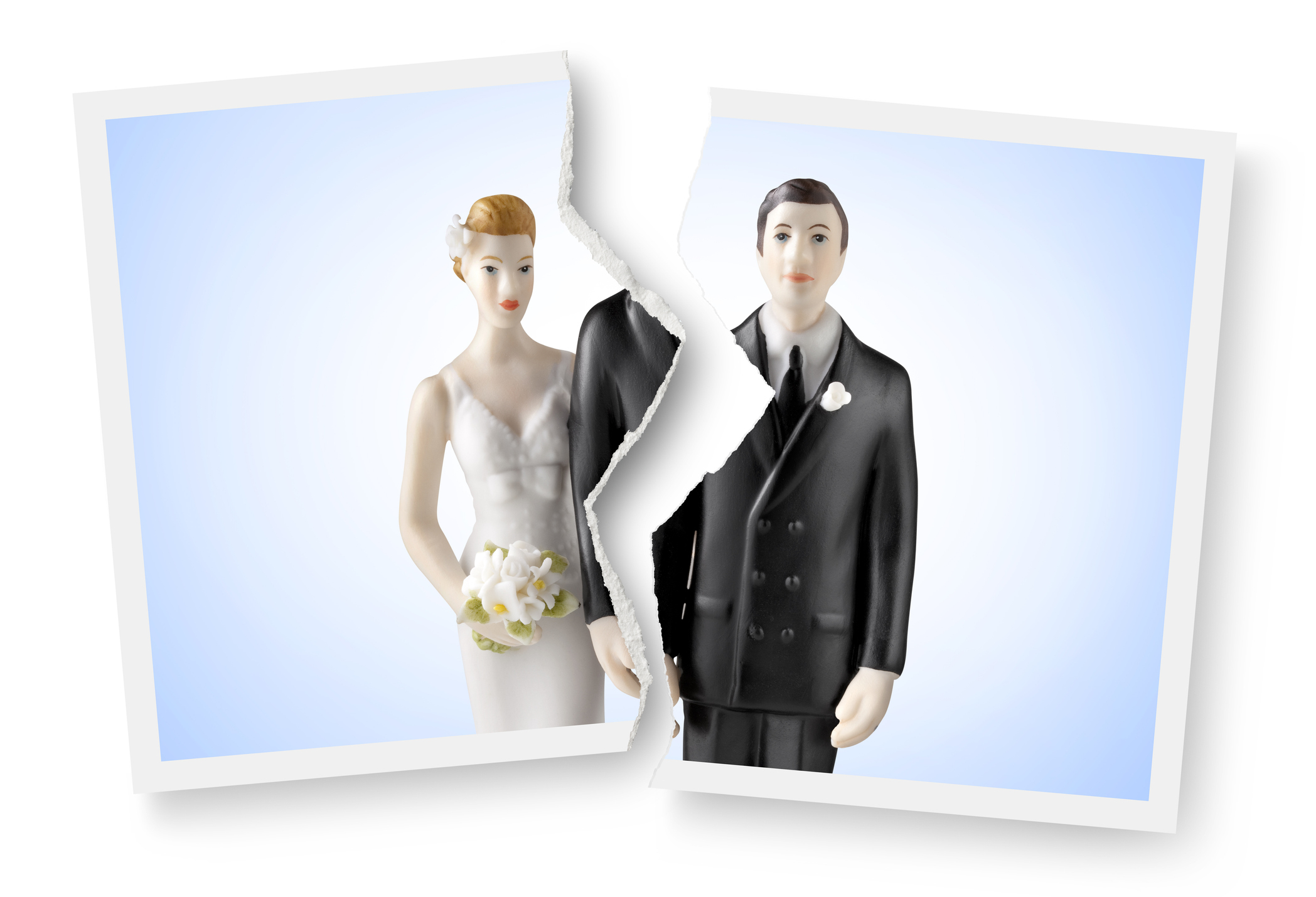 Torn photo of a bride and groom figurine, representing relationship end