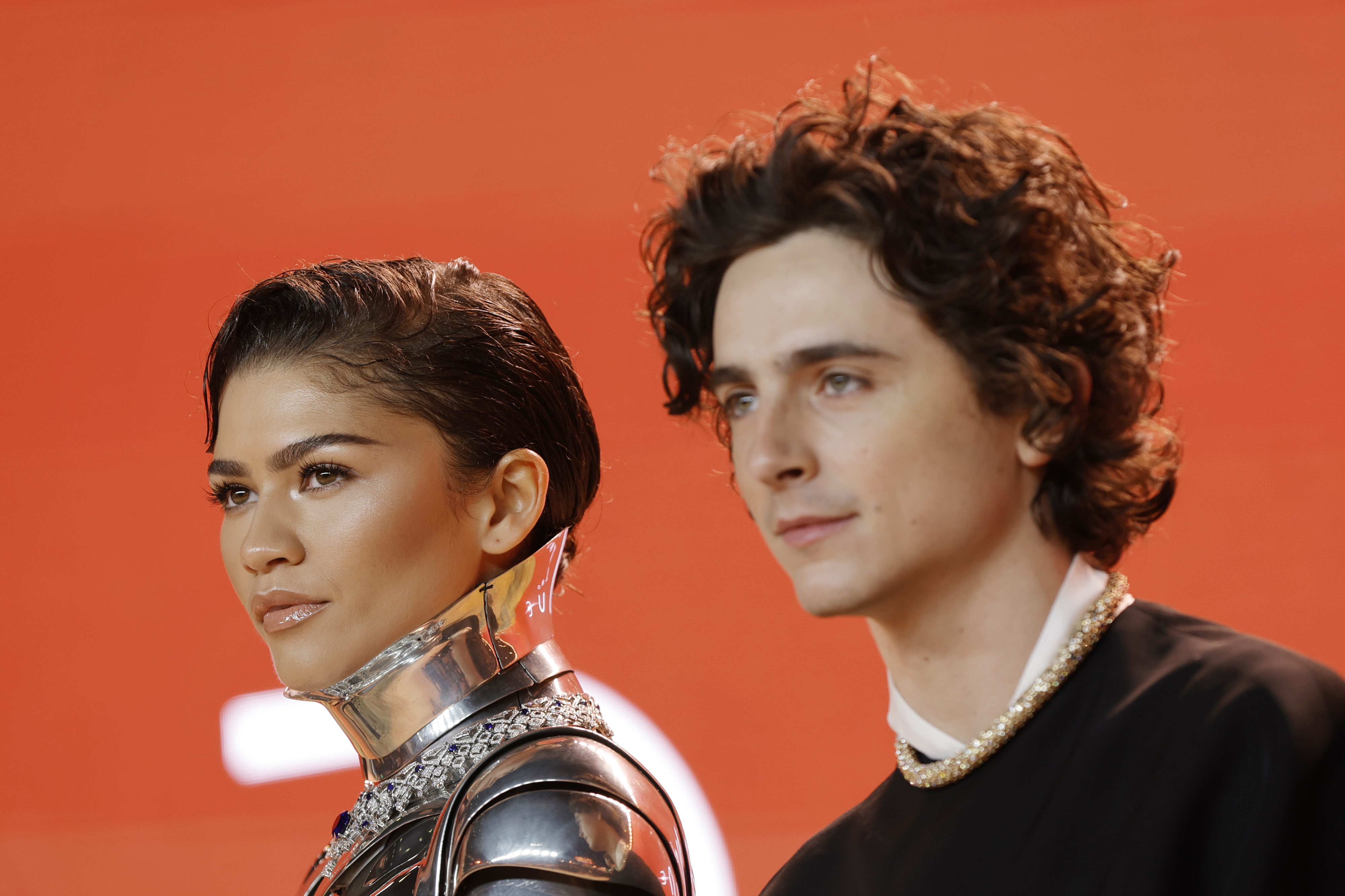 Zendaya in a metallic outfit and Timothée Chalamet in a black suit pose side by side