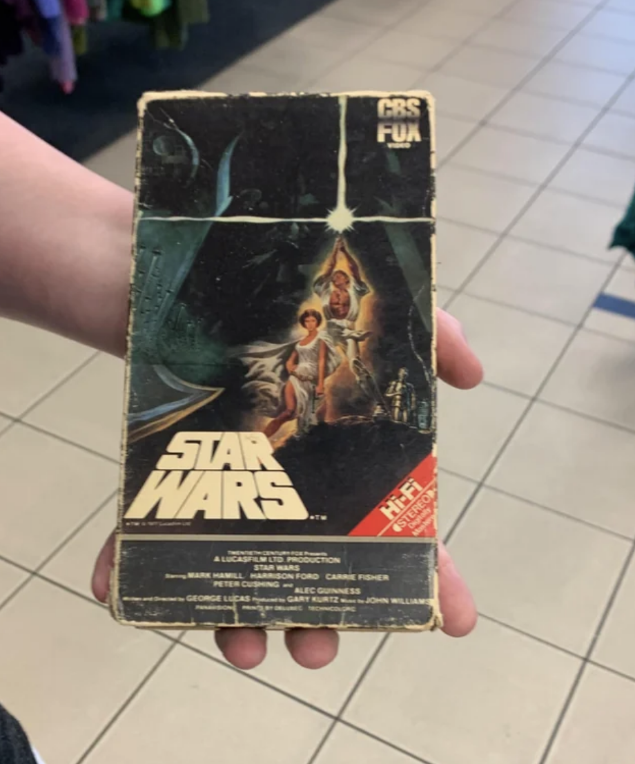 Hand holding a worn-out original Star Wars VHS tape cover, featuring classic movie art