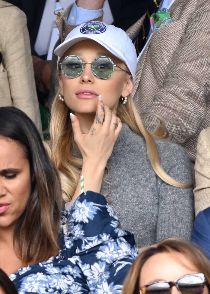 Ariana Grande wearing a cap and sunglasses at a public sports event
