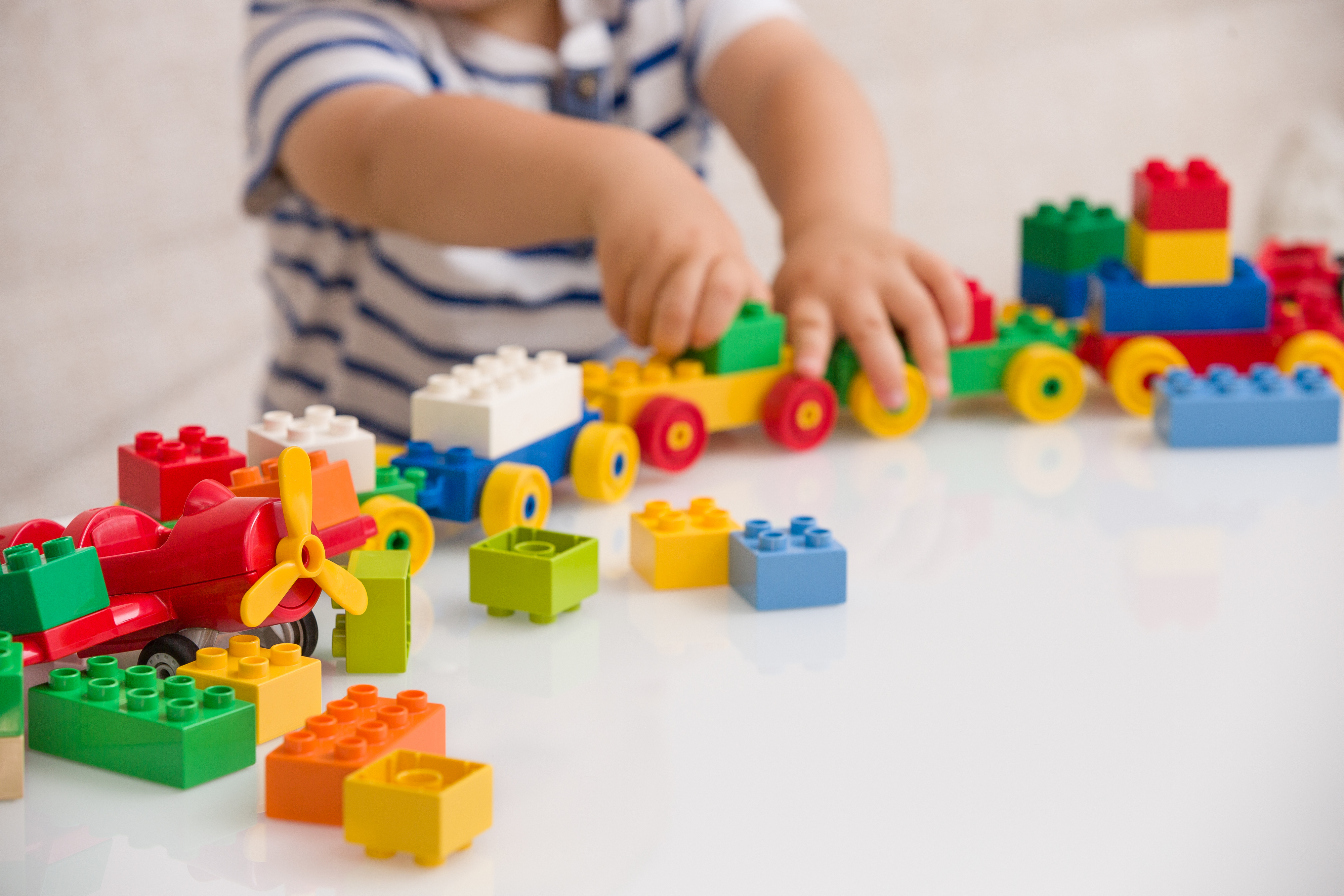 Child playing with a variety of plastic building blocks on a table