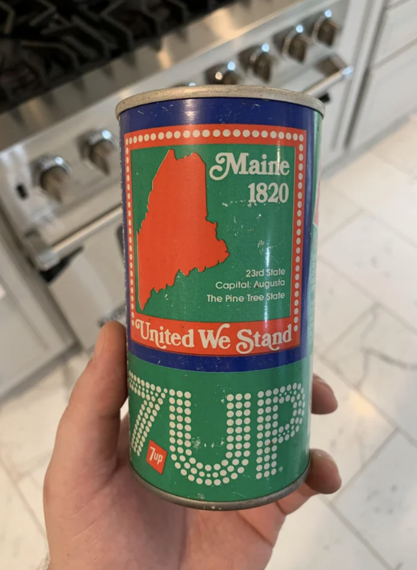Vintage Maine-themed soda can with state outline, slogan &quot;United We Stand,&quot; held in a kitchen