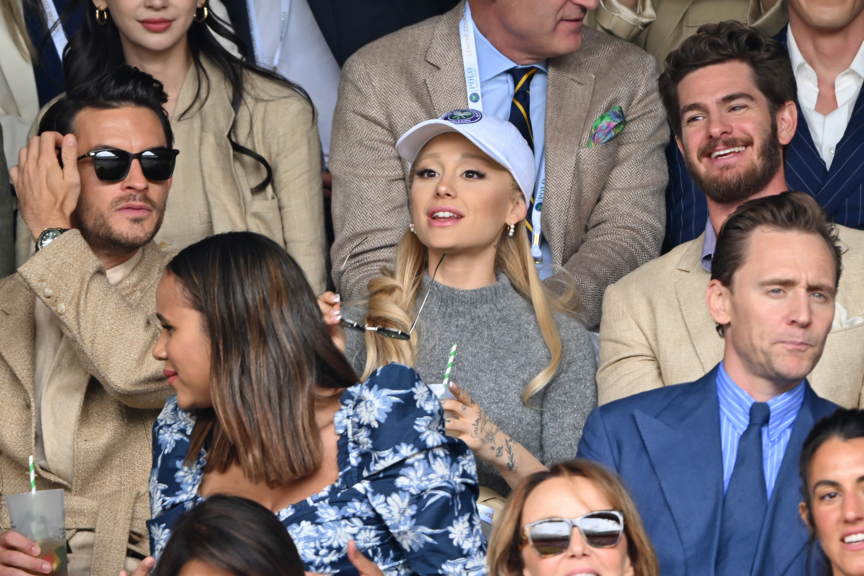 Ariana Grande in a crowd sitting in between Jonathan Bailey and Andrew Garfield