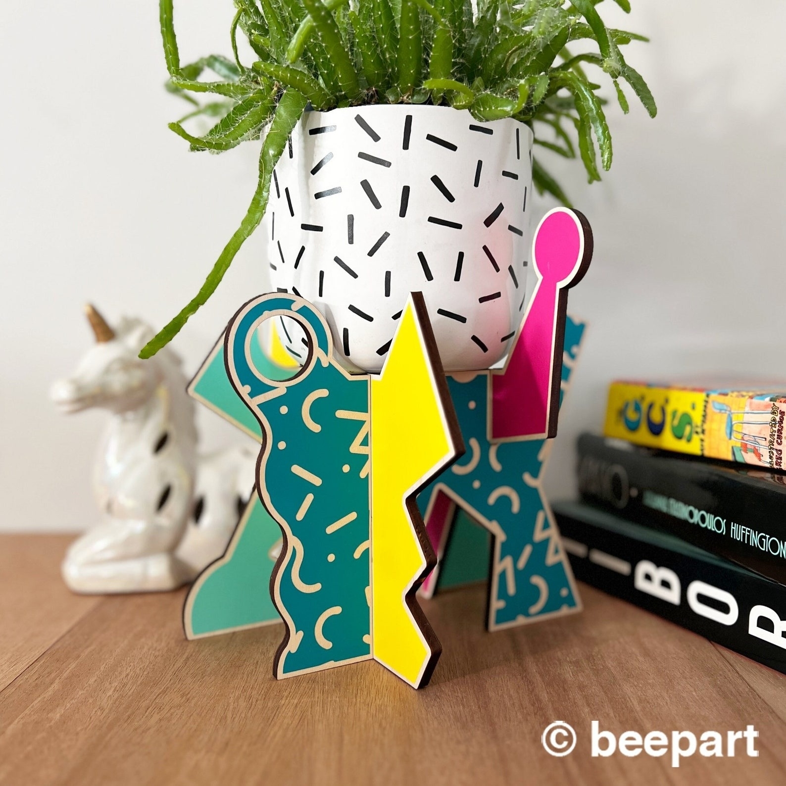 Decorative plant stand with abstract design holding a plant pot on a wooden surface
