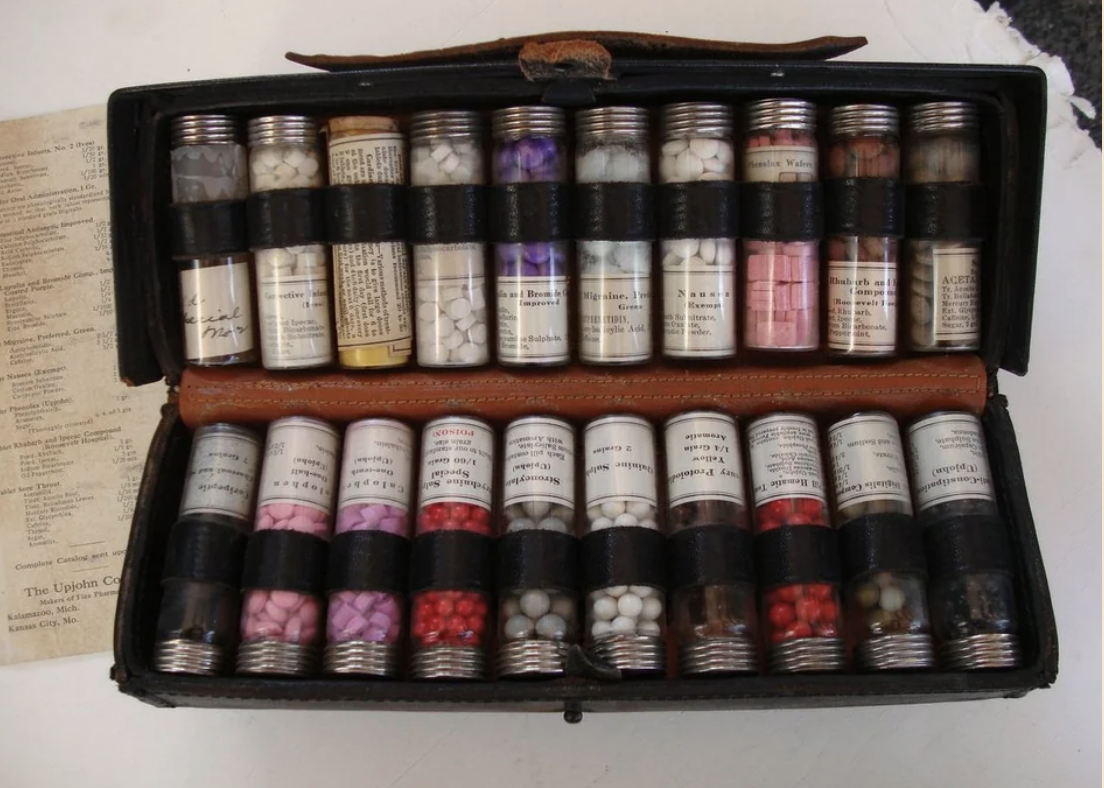 Vintage medicine kit with multiple labeled bottles and capsules, open on a table