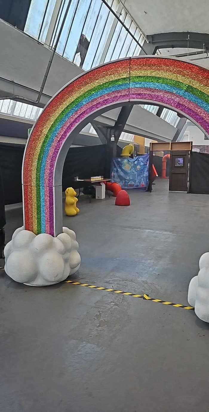 A rainbow archway entrance with cloud designs and oversize yellow duck sculptures in an indoor space