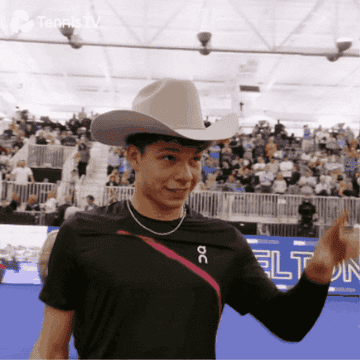 Tenista profesional sonriendo y saludando con un sombrero vaquero grande