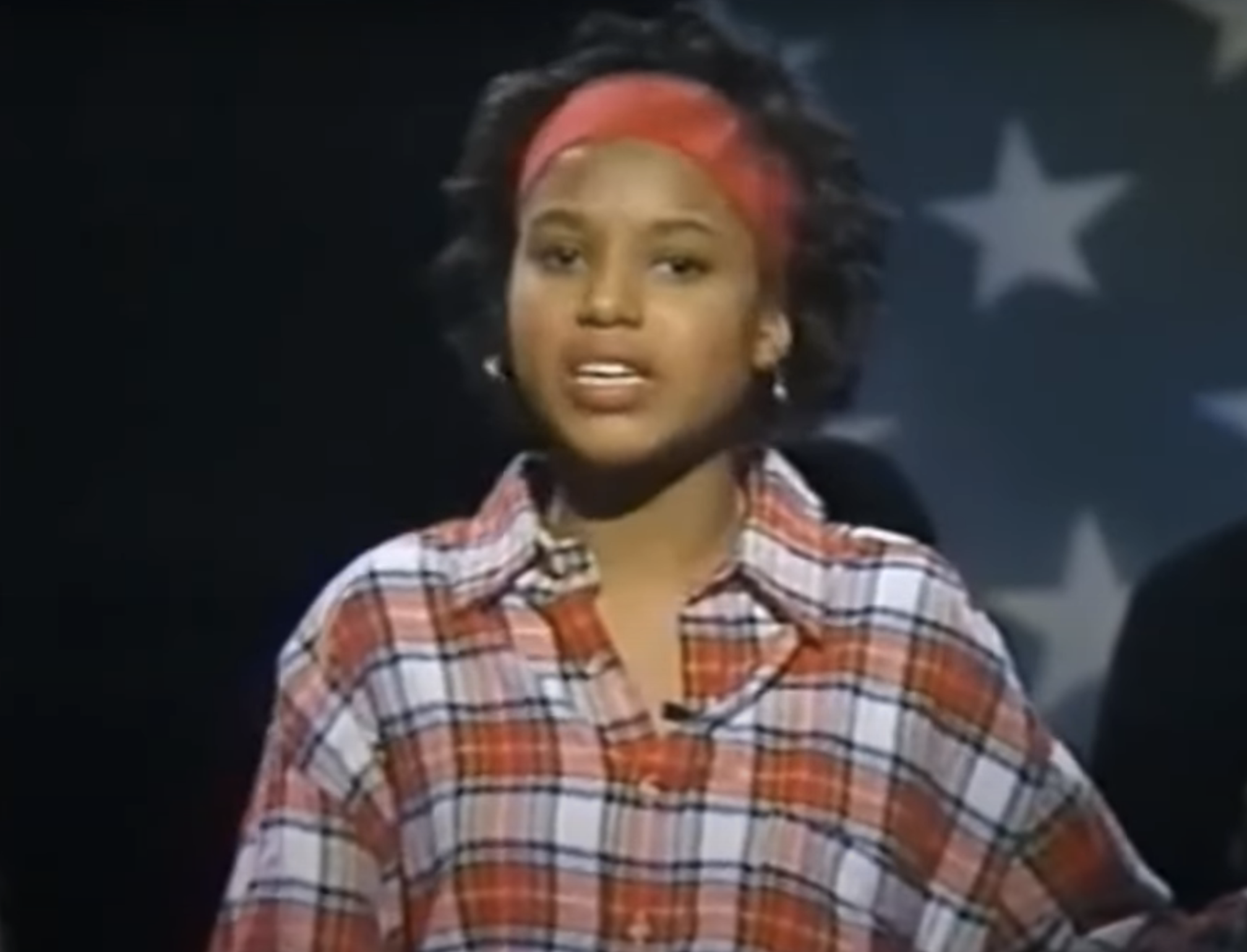 Kerry in a plaid shirt with a headband against a starry backdrop