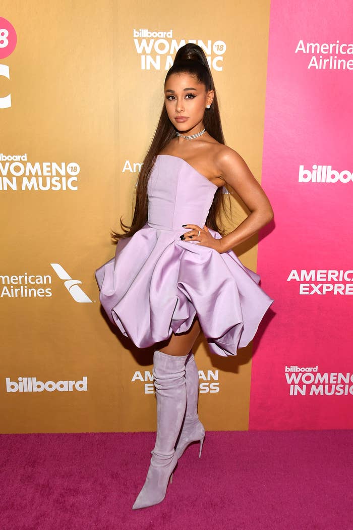 Ariana Grande poses at an event in a strapless dress and thigh-high boots